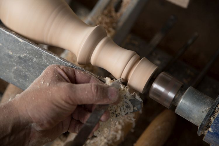 Carpenter turning hard wood on a lathe hands close up